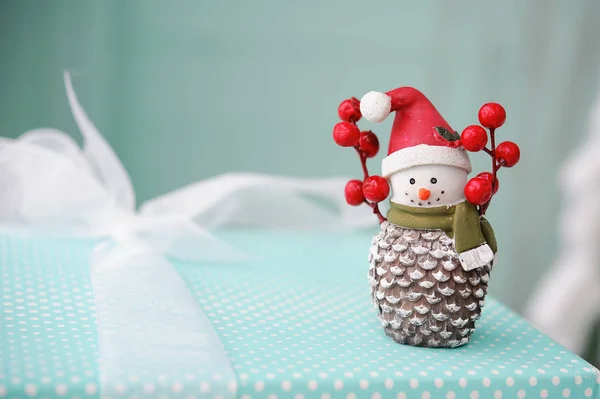 Muñeco de nieve de juguete sobre fondo turquesa, regalos de Navidad — Foto de Stock