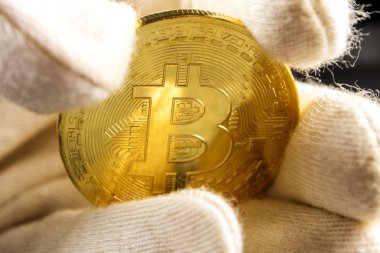 adam beyaz eldivenli bir altın bitcoin elinde tutuyor