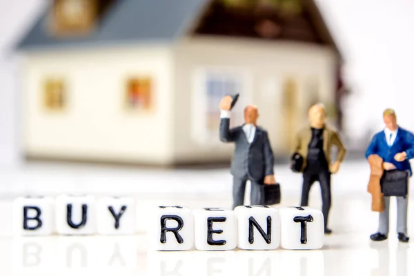the decision about rent or buy a new residence as an investment oportunity, a team of miniature figurines deciding about a new financial possibility, rent and buy white dices