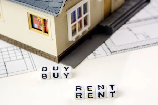 the decision about rent or buy a new residence as an investment oportunity, a team of miniature figurines deciding about a new financial possibility, rent and buy white dices