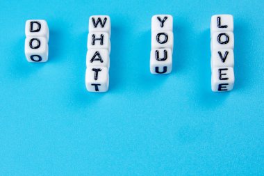 Bir metin oluşturan küçük beyaz zarlar mavi arkaplan üzerinde pozitif yaşam tarzı teması olarak sevdiğiniz şeyi yapın