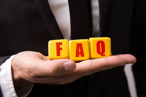 Mão segurando um cubo com o texto: FAQ (Perguntas Frequentes ) — Fotografia de Stock