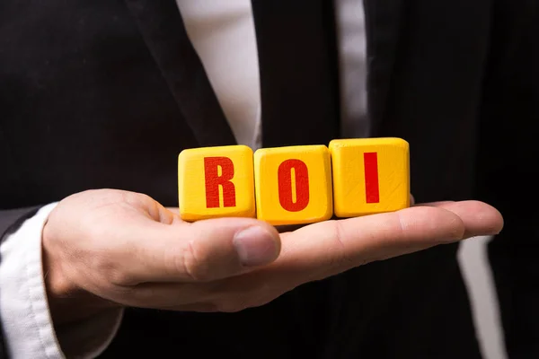 Hand hält einen Würfel mit dem Text: roi (Return on Investment)) — Stockfoto