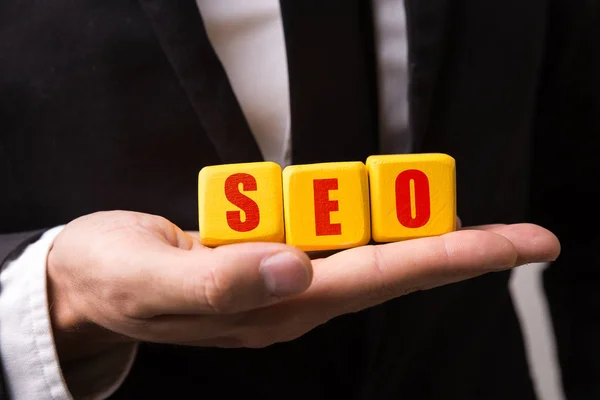 Mão segurando um cubo com o texto: SEO (search engine optimization ) — Fotografia de Stock