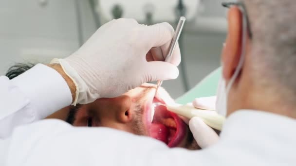 Dentista curando a un paciente masculino — Vídeos de Stock