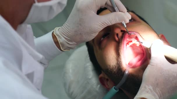 Dentista curando a un paciente masculino — Vídeo de stock