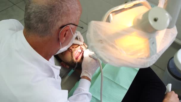 Dentista cura um paciente do sexo masculino — Vídeo de Stock