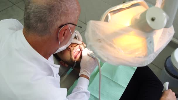 Dentista curando a un paciente masculino — Vídeo de stock