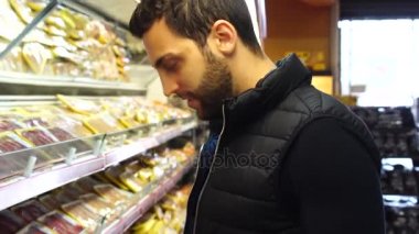 Genç adam süpermarkette alışveriş yapıyor.