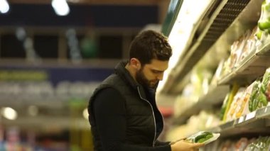 Genç adam süpermarkette alışveriş yapıyor.