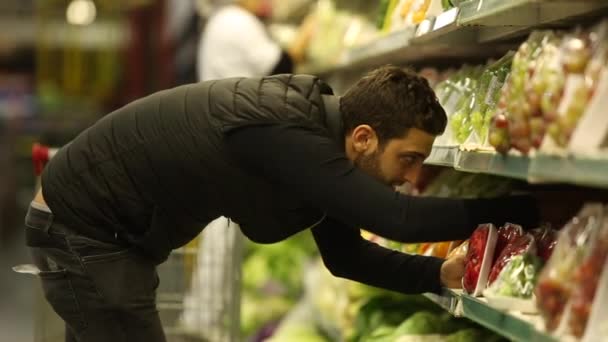 Junger Mann kauft im Supermarkt ein — Stockvideo
