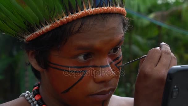 Hombre nativo brasileño (Indio) Pintura en su rostro en una tribu indígena — Vídeos de Stock