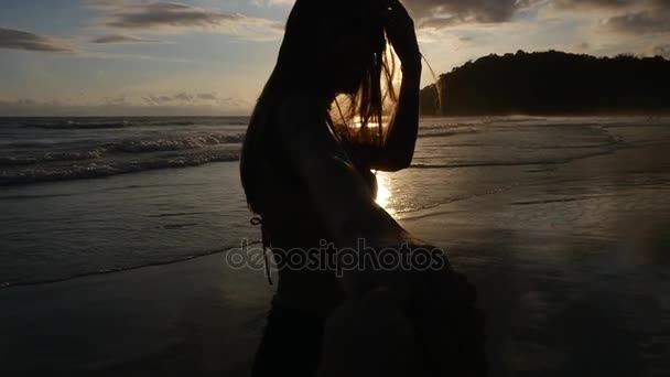 Vue arrière d'un couple qui s'amuse et se tient la main sur la plage - Slow Motion 