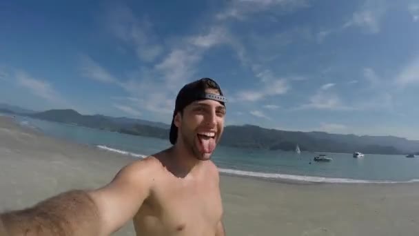 Hombre tomando una selfie y divirtiéndose en una playa en Brasil — Vídeo de stock