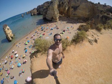 Guy Taking a Selfie in Algarve Beach, Portugal clipart