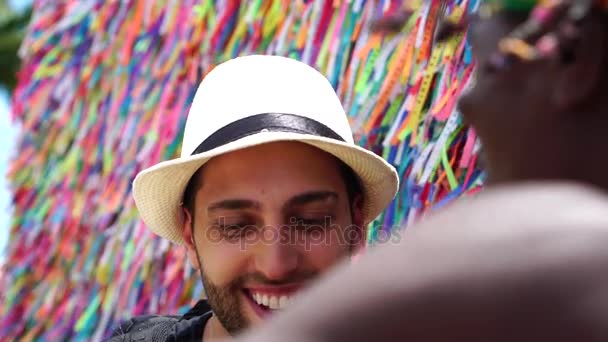 Hombre brasileño dando la bienvenida al turista dando algunas "cintas de deseos brasileños" en Salvador, Brasil - las cintas se consideran encantos de buena suerte — Vídeo de stock