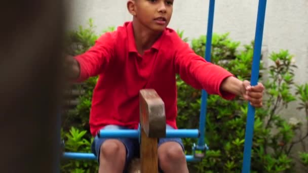 Мальчик, играющий на качелях — стоковое видео