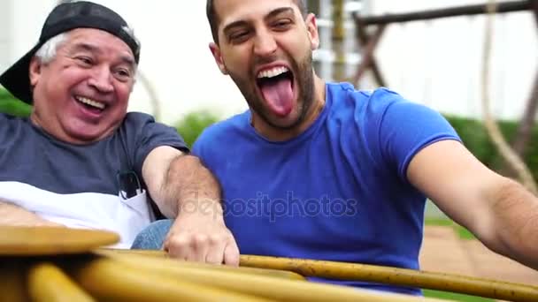 Папа и сын играют на карусели — стоковое видео
