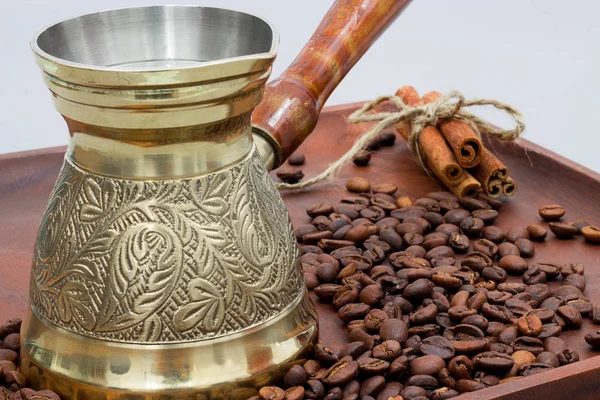 Copper coffee pot with coffee beans and cinnamon sticks. On a wooden plate board. White background