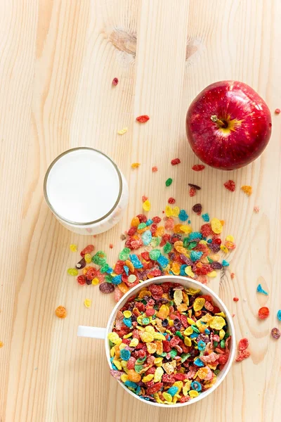 Kids healthy quick breakfast. Colorful rice cereal, milk and red apple for kids on wooden background.