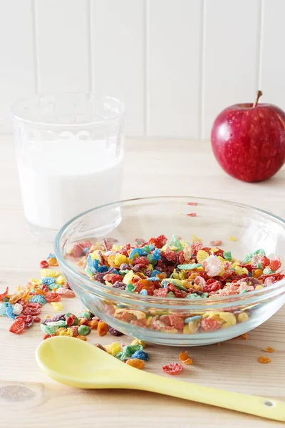 Colorful rice cereal with milk and red apple for children. Healthy quick breakfast. Wooden background. Copy space. Selective focus.