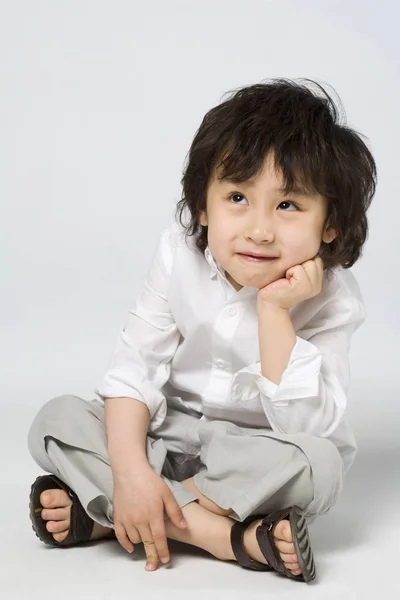 灰色の背景にあごに手を持ったアジア少年の肖像画 — ストック写真