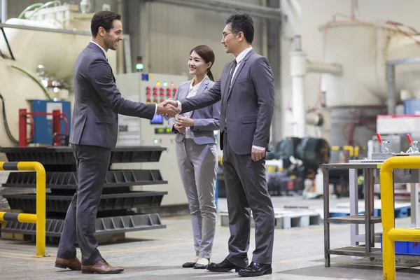 Businessmen shaking hands at industrial factory — Stock Photo