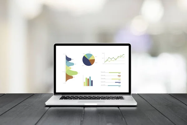 Laptop on wooden table showing charts and graph — Stock Photo, Image