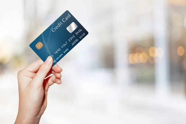 Θηλυκό χέρι κρατώντας πιστωτική κάρτα κατά θολούρα υπαίθρια ψώνια ma — Φωτογραφία Αρχείου