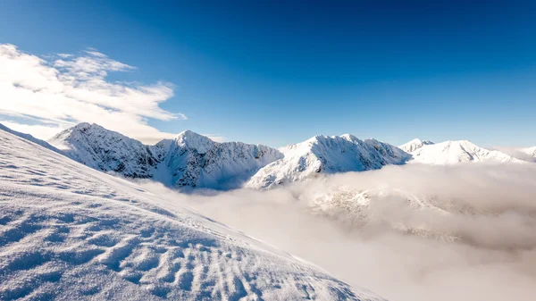 Cumes de montanha no inverno coberto de neve com sol brilhante e azul — Fotografia de Stock