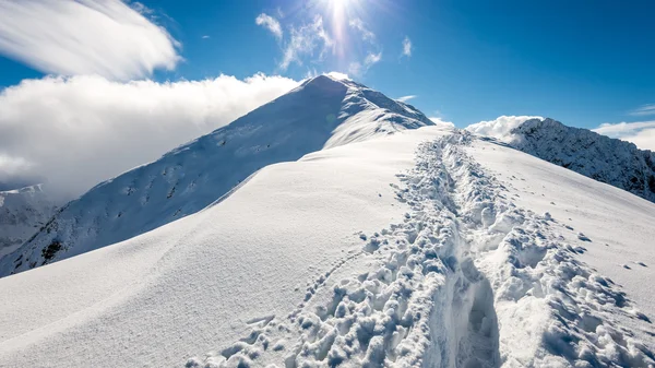 Berggipfel im Winter schneebedeckt mit heller Sonne und blauem Himmel — Stockfoto