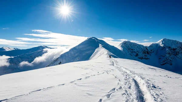 Bergtoppen in de winter bedekt met sneeuw met felle zon en blauw — Stockfoto