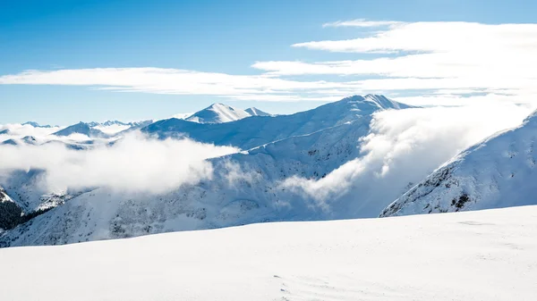 Cumes de montanha no inverno coberto de neve com sol brilhante e azul — Fotografia de Stock