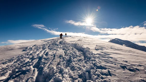 Turistas desfrutando de altas montanhas na neve em um dia ensolarado — Fotografia de Stock