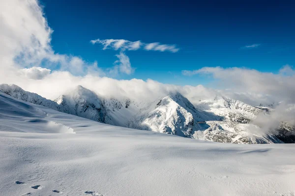 Cumbres de montaña en invierno cubiertas de nieve con sol brillante y azul — Foto de Stock