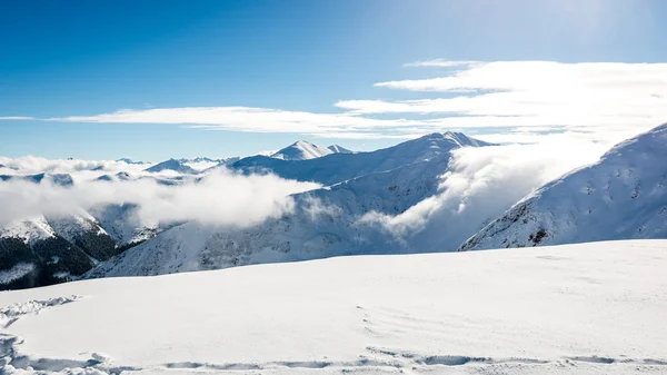 Cumbres de montaña en invierno cubiertas de nieve con sol brillante y azul — Foto de Stock