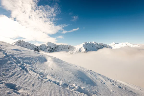 Cumes de montanha no inverno coberto de neve com sol brilhante e azul — Fotografia de Stock