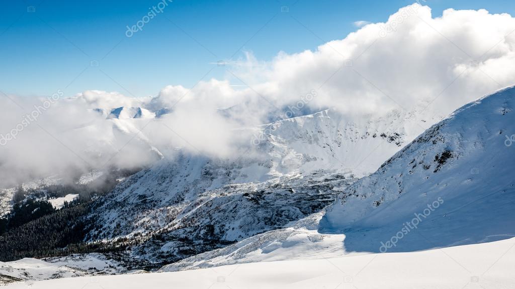 mountain tops in winter covered in snow with bright sun and blue