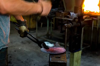 El ile örs üzerinde erimiş metal dövme demirci