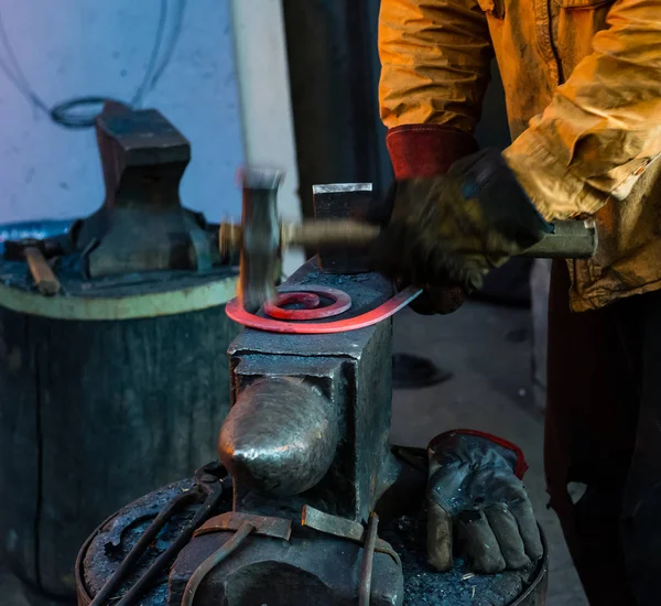 El herrero forja manualmente el metal fundido en el yunque — Foto de Stock