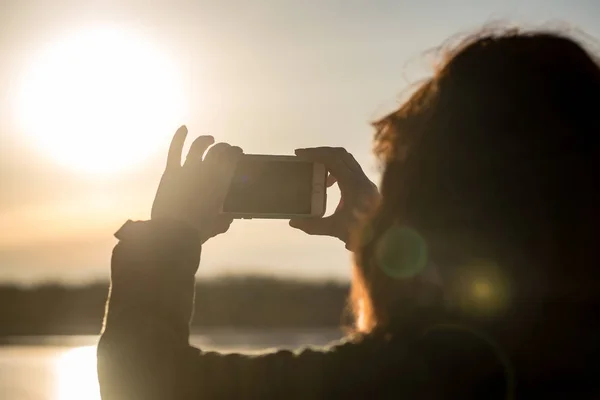 O tânără care fotografiază soarele cu telefonul mobil. oameni care se bucură — Fotografie, imagine de stoc