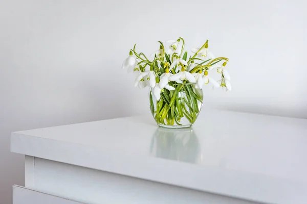 Flores de primavera em um vaso na mesa leve no quarto branco — Fotografia de Stock