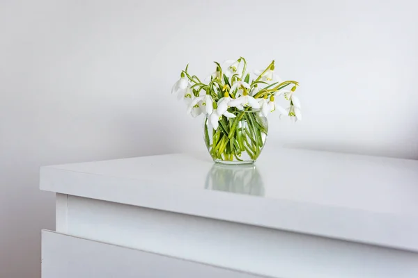 Flores de primavera em um vaso na mesa leve no quarto branco — Fotografia de Stock