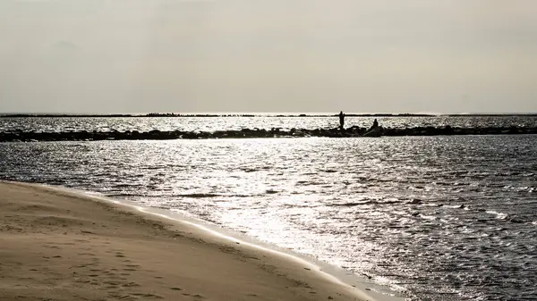 Névtelen személy gyaloglás-ra egy homok szeles strandon — Stock Fotó