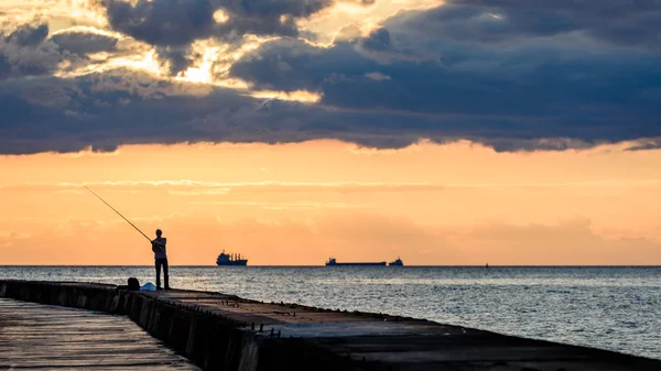 People enjoying sunset on the breakwater in the sea with lightho — Stock Photo, Image