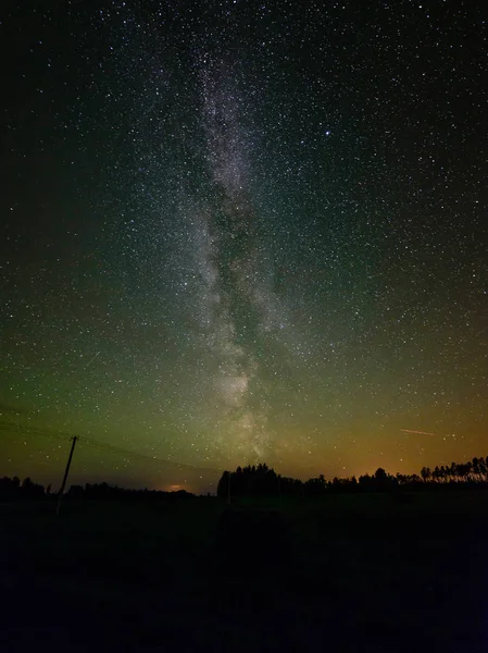 La Vía Láctea en el cielo nocturno con estrellas y algunos árboles . — Foto de Stock