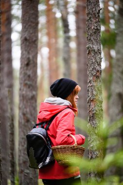 ormandaki doğanın keyfini kırmızı ceketli genç kadın. Letonya