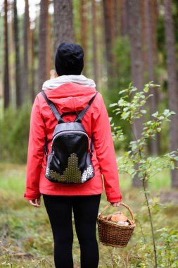 ormandaki doğanın keyfini kırmızı ceketli genç kadın. Letonya