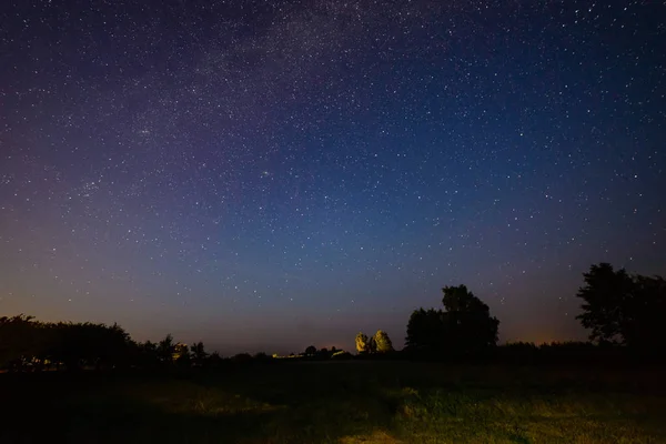 Colorida galaxia de la Vía Láctea vista en el cielo nocturno sobre árboles — Foto de Stock