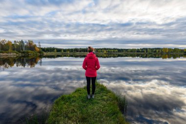 genç kadın doğa toprak yol üzerinde kırmızı ceketli. Letonya